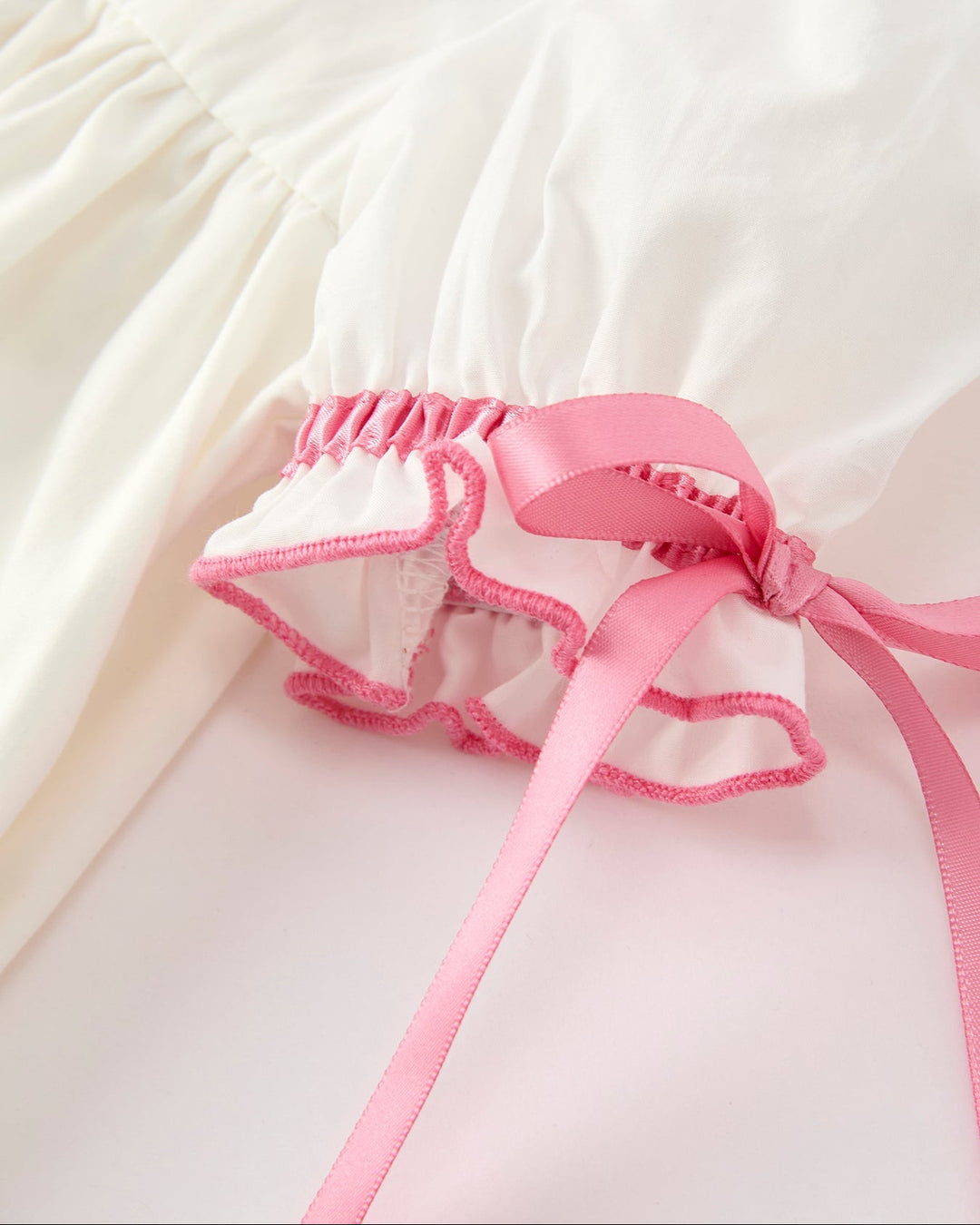 Girls cream dress with pink ruffled hem and bow-tied lace-trimmed underlayer