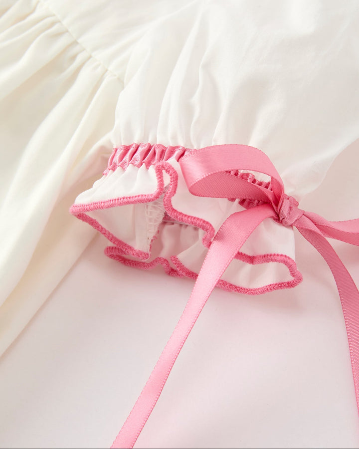 Girls cream dress with pink ruffled hem and bow-tied lace-trimmed underlayer