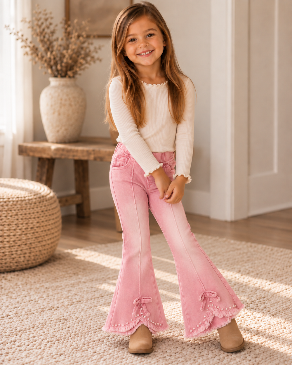 Pink flare jeans on a child with bow-and-pearl accents at the cuffs and hem