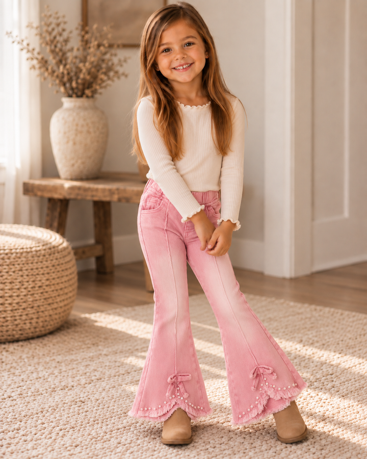 Pink flare jeans on a child with bow-and-pearl accents at the cuffs and hem