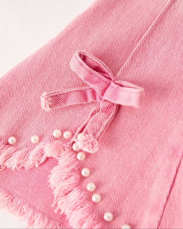 Pink denim flared jeans with bow and pearl-like bead hem detail
