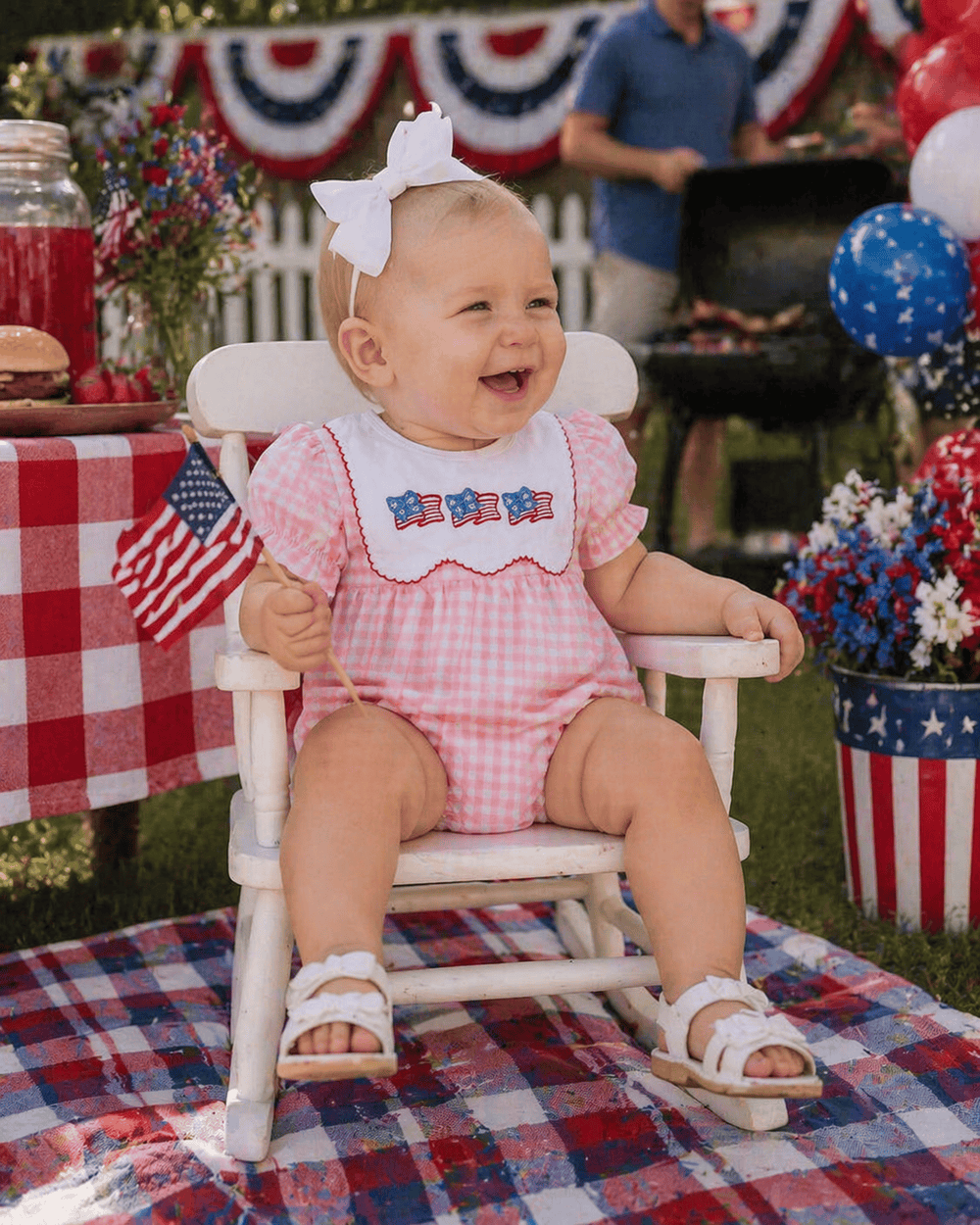 Baby in a high chair wearing a patriotic outfit with a 4th of July theme.