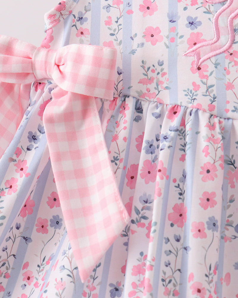 Floral dress with pink checkered sleeves and trim on a white background