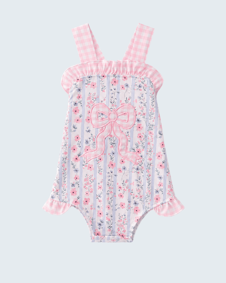 Floral and striped romper with a bow on a light gray background