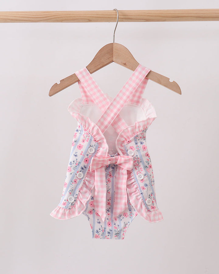 Pink floral baby romper on a hanger against a white background