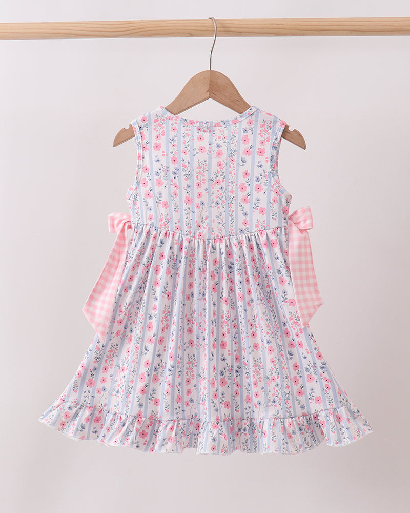 Floral dress with pink accents on a wooden hanger against a beige background