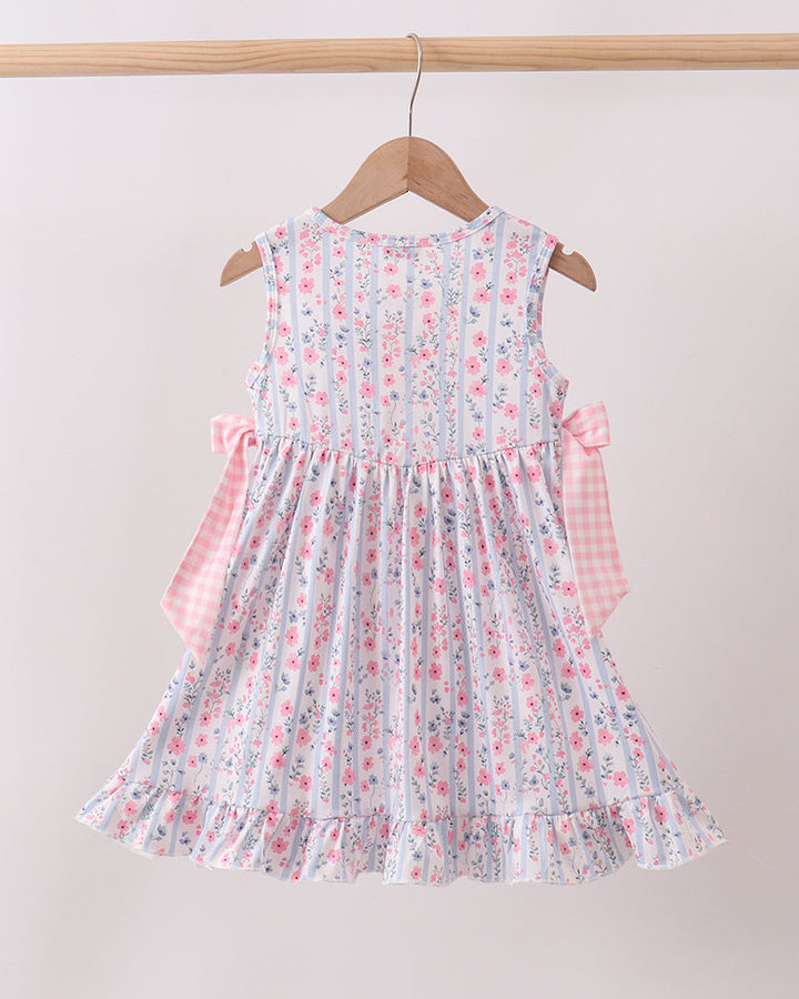 Floral dress with pink accents on a wooden hanger against a beige background