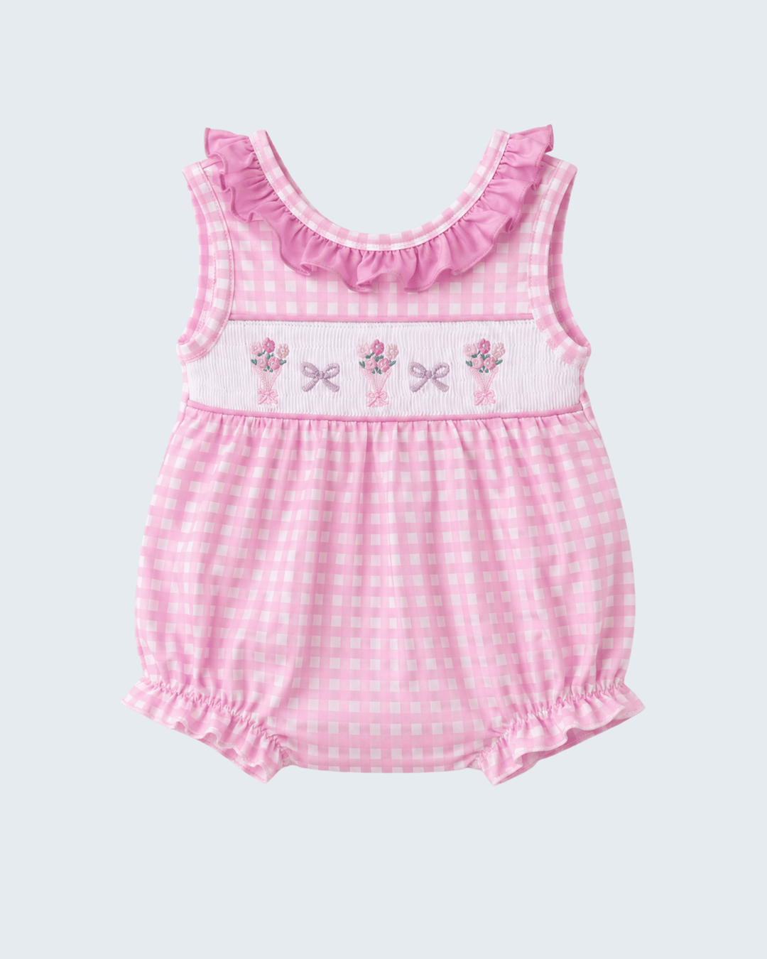 Pink checkered baby romper with floral and bow details on a light gray background