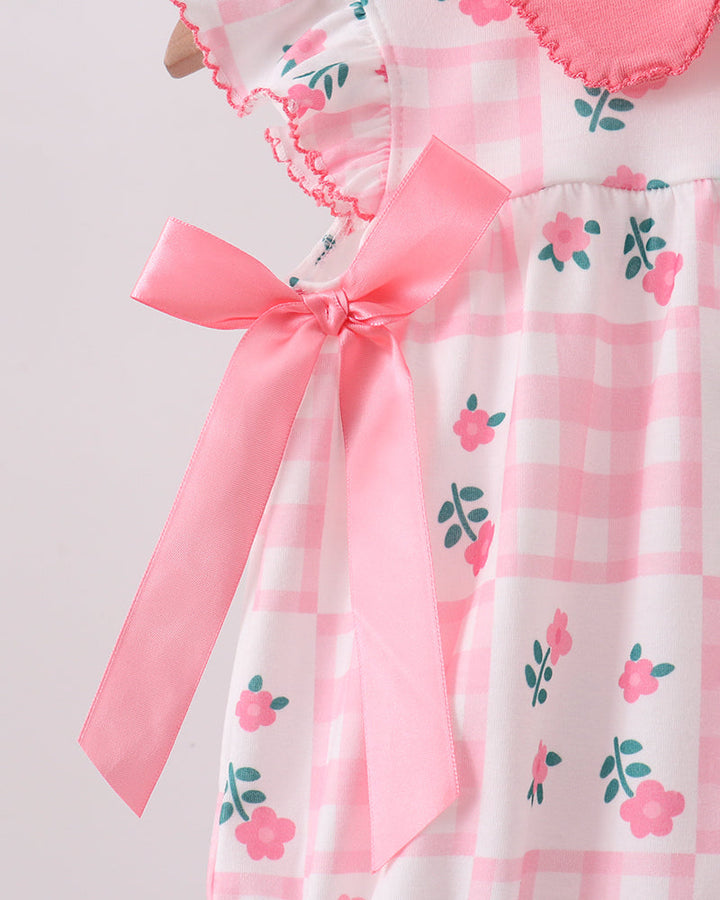 Pink and white checkered dress with floral patterns and a large pink bow on a light gray background