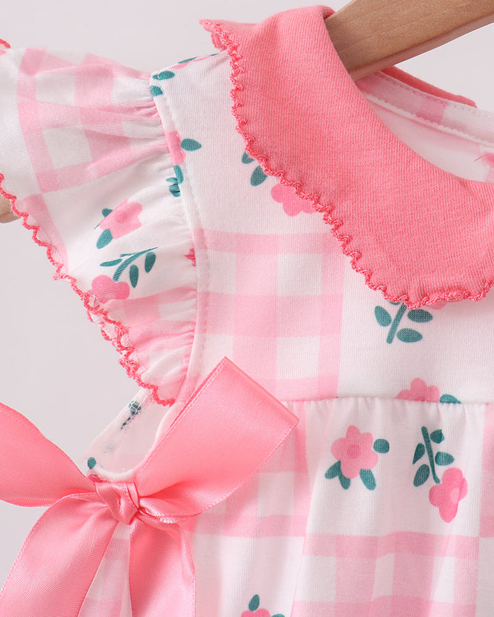 Close-up of a baby romper with floral pattern and pink ruffled collar on a white background