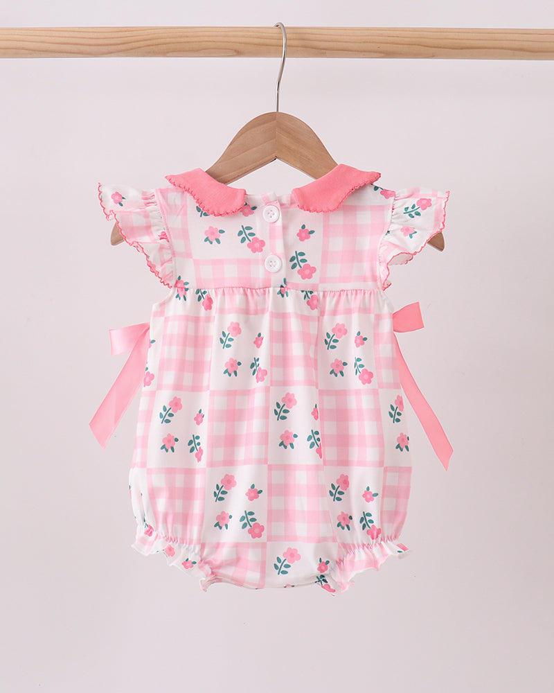 Pink floral baby romper on a wooden hanger against a light gray background