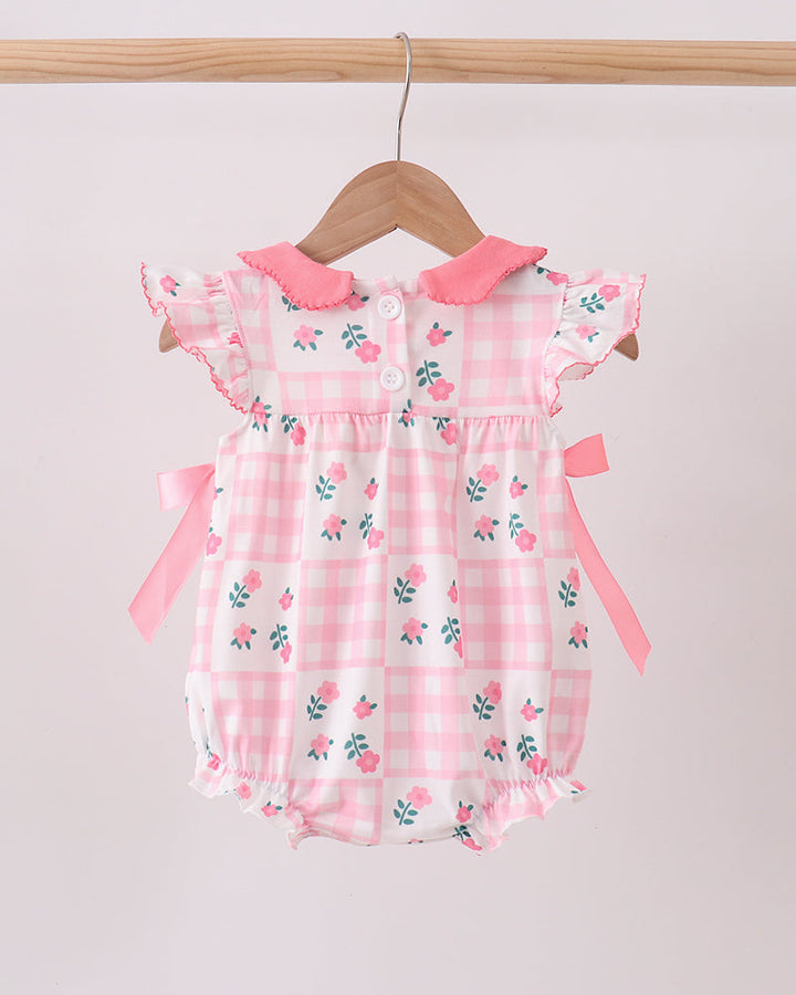 Pink floral baby romper on a wooden hanger against a light gray background