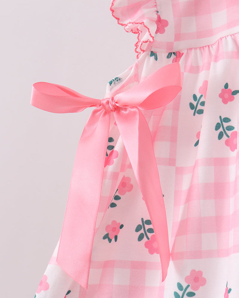 Pink dress with floral pattern and bow on a light gray background