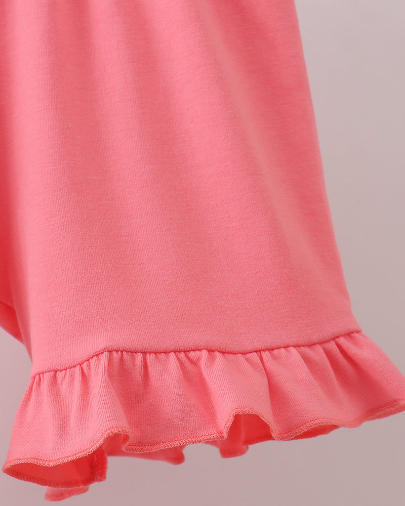Close-up of a pink dress with ruffled hem on a light gray background