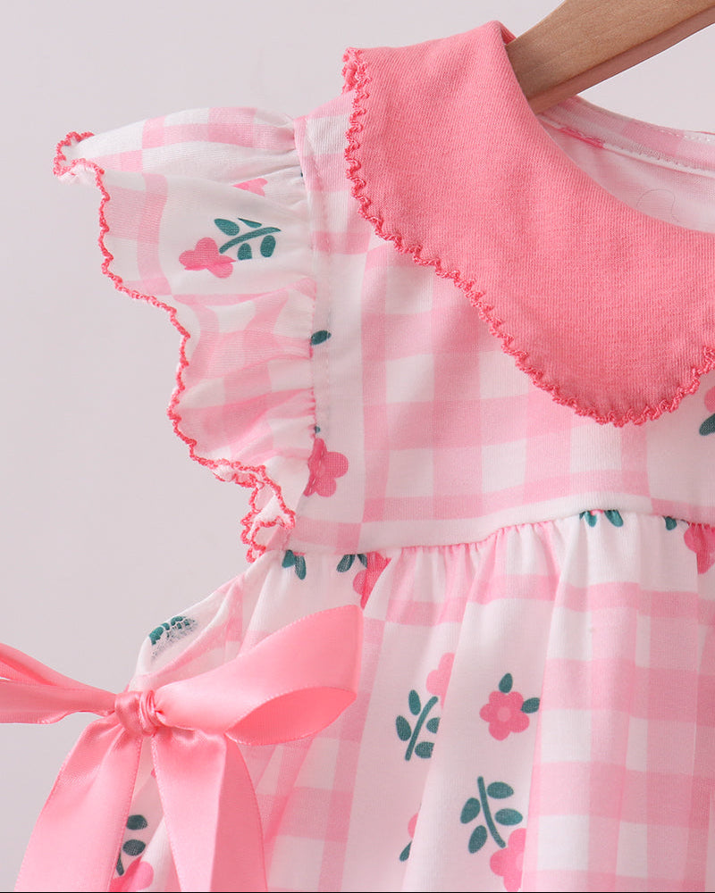 Close-up of a pink and white checkered dress with floral patterns on a light gray background