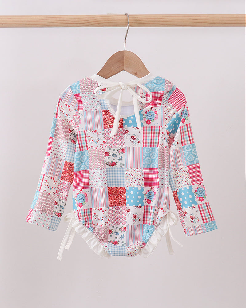 Colorful patchwork rashguard on a hanger against a plain background