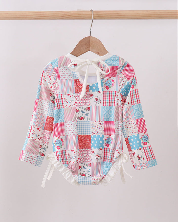 Colorful patchwork rashguard on a hanger against a plain background