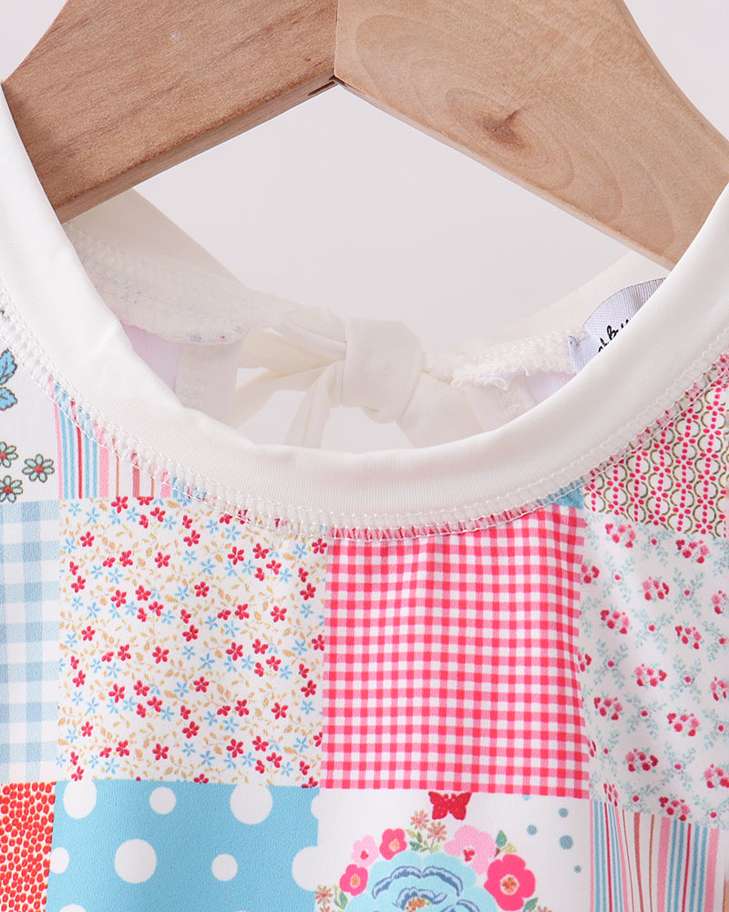 Patchwork fabric with floral, polka dot, and checkered patterns on a wooden hanger.