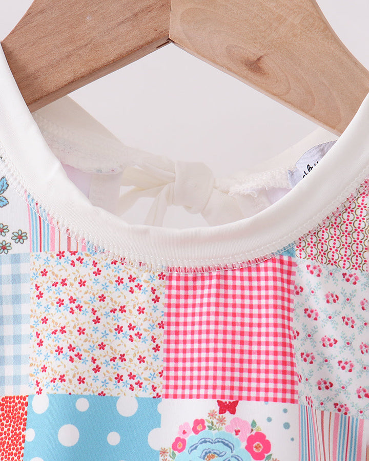 Patchwork fabric with floral, polka dot, and checkered patterns on a wooden hanger.