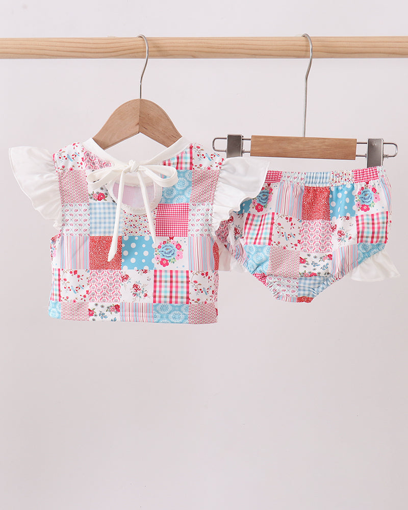 Patchwork baby outfit with top and shorts on a hanger against a white background