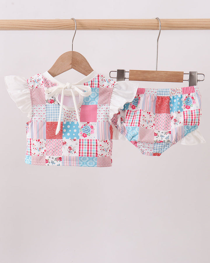 Patchwork baby outfit with top and shorts on a hanger against a white background