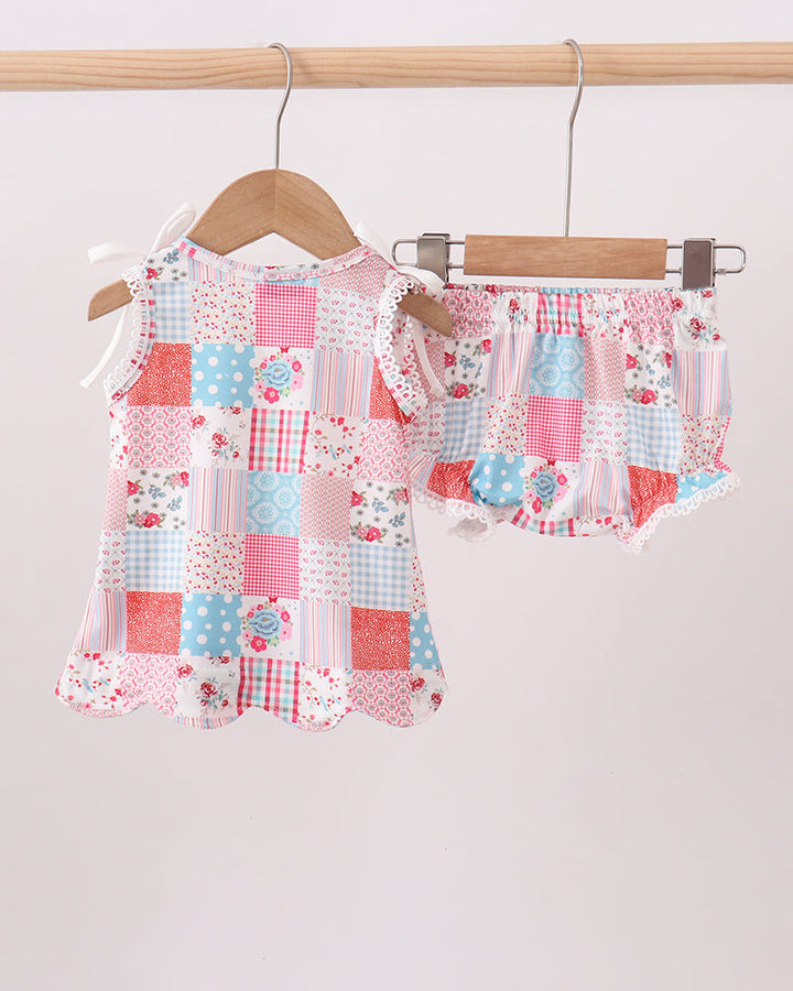 Patchwork baby outfit on a hanger against a white background