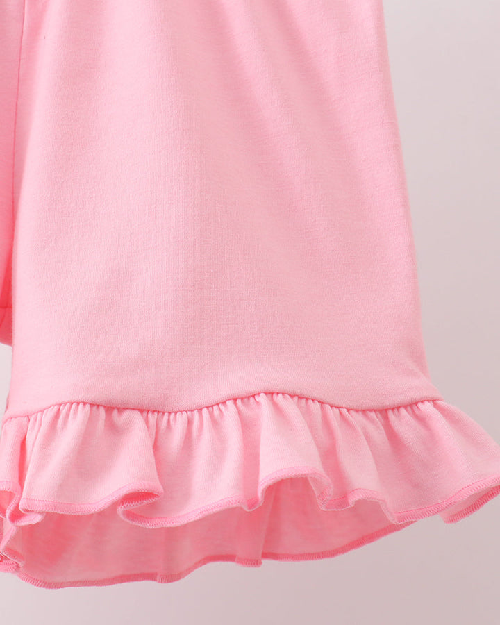 Close-up of a pink shorts with ruffled hem on a light gray background