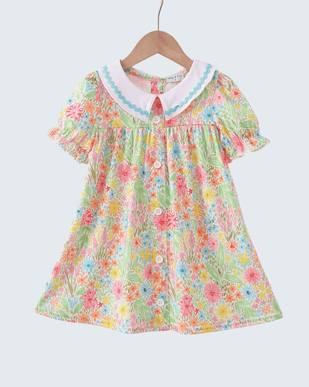 Colorful floral dress on a hanger against a white background