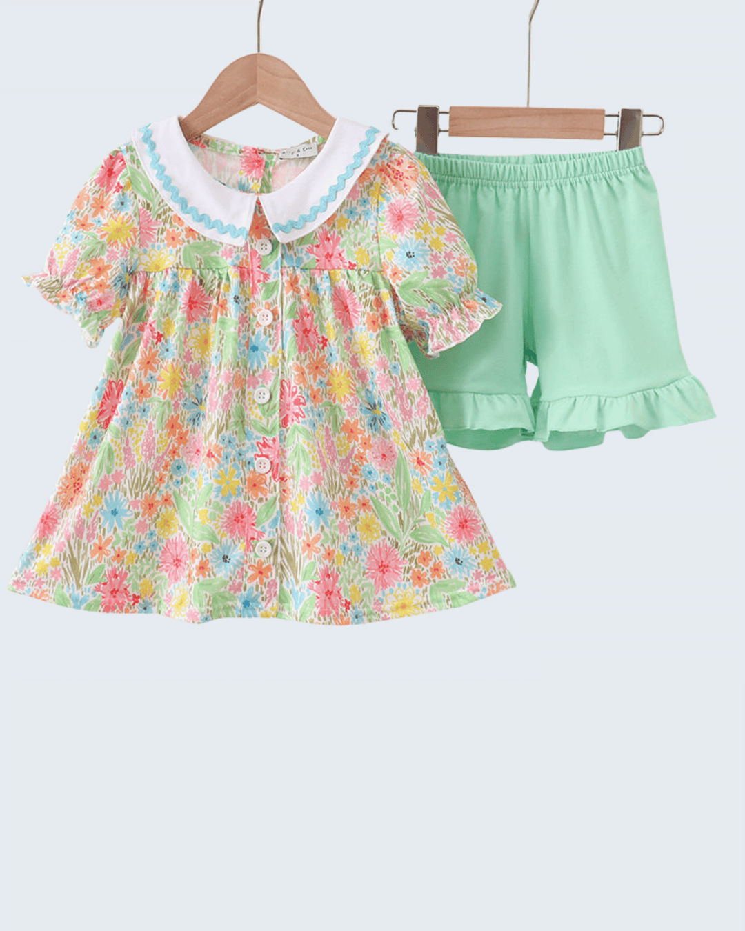 Children's floral dress and green shorts set on a white background