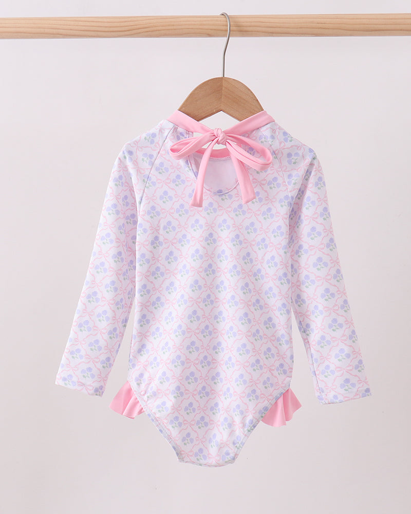 Rashguard with floral pattern and pink accents on a hanger against a white background