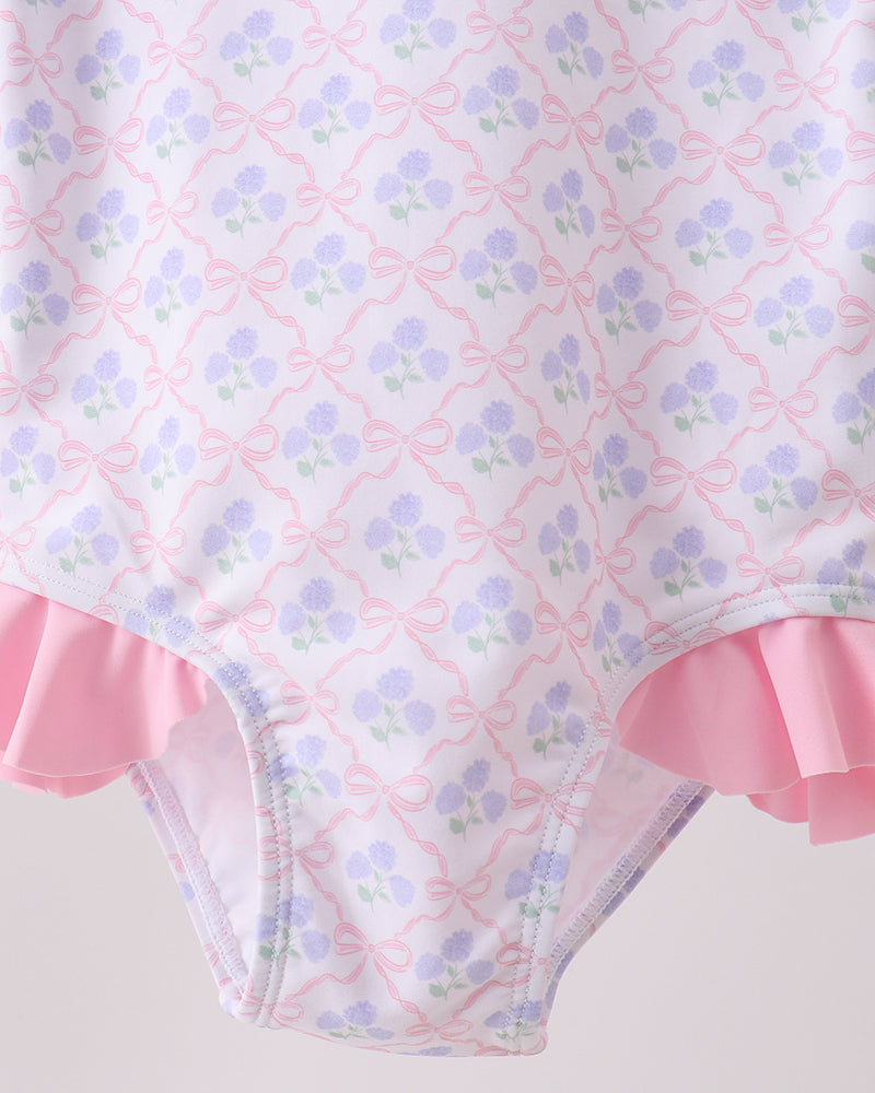 Floral patterned swimsuit with pink ruffles on a light background