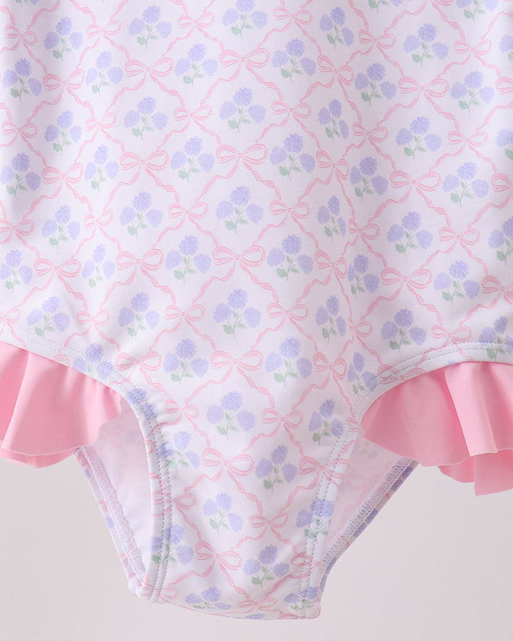 Floral patterned swimsuit with pink ruffles on a light background