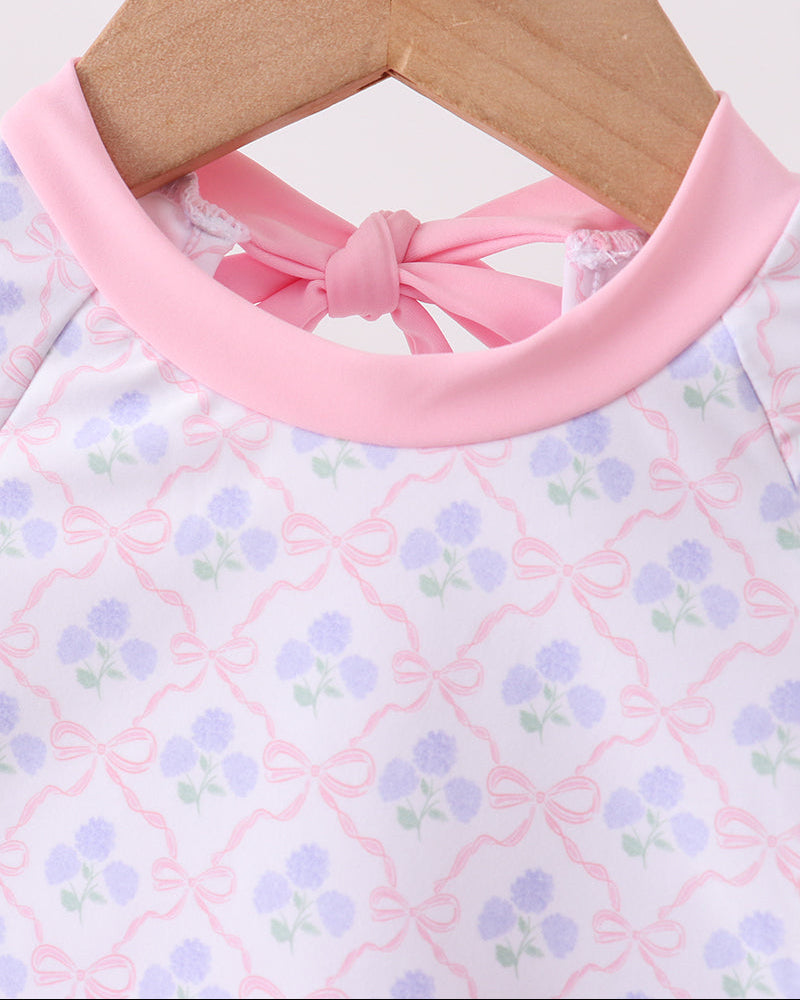 Rashguard with pink collar and floral pattern on a wooden hanger