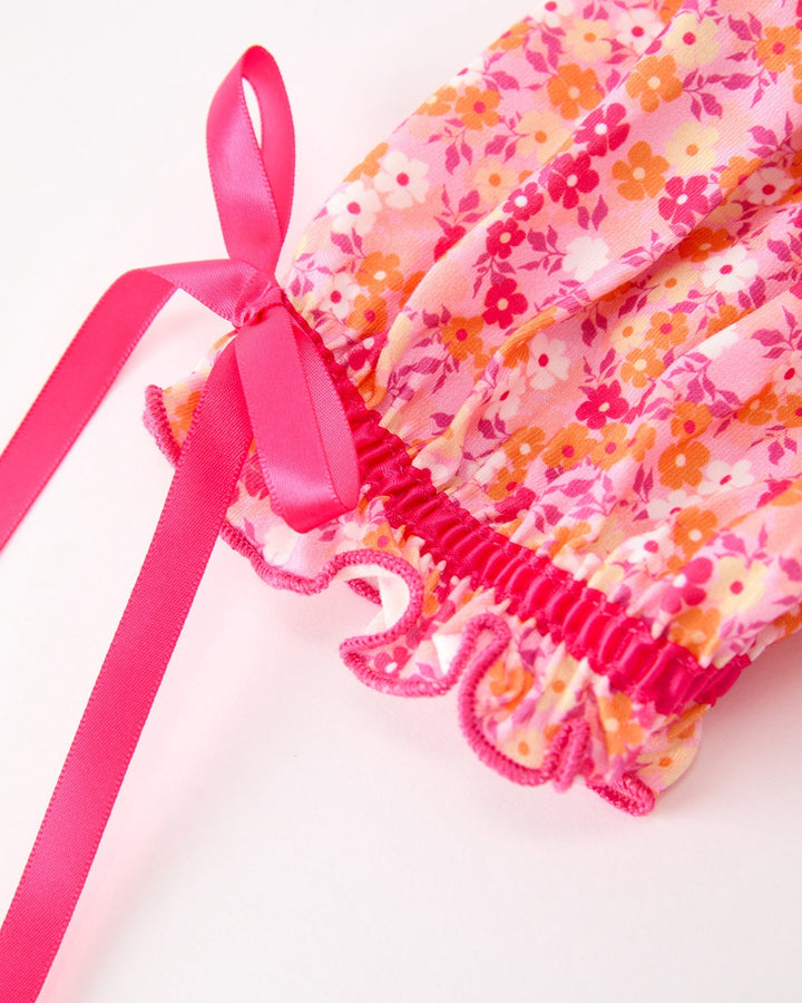 Pink floral twirl dress hem with smocked detail and long satin ribbon ties