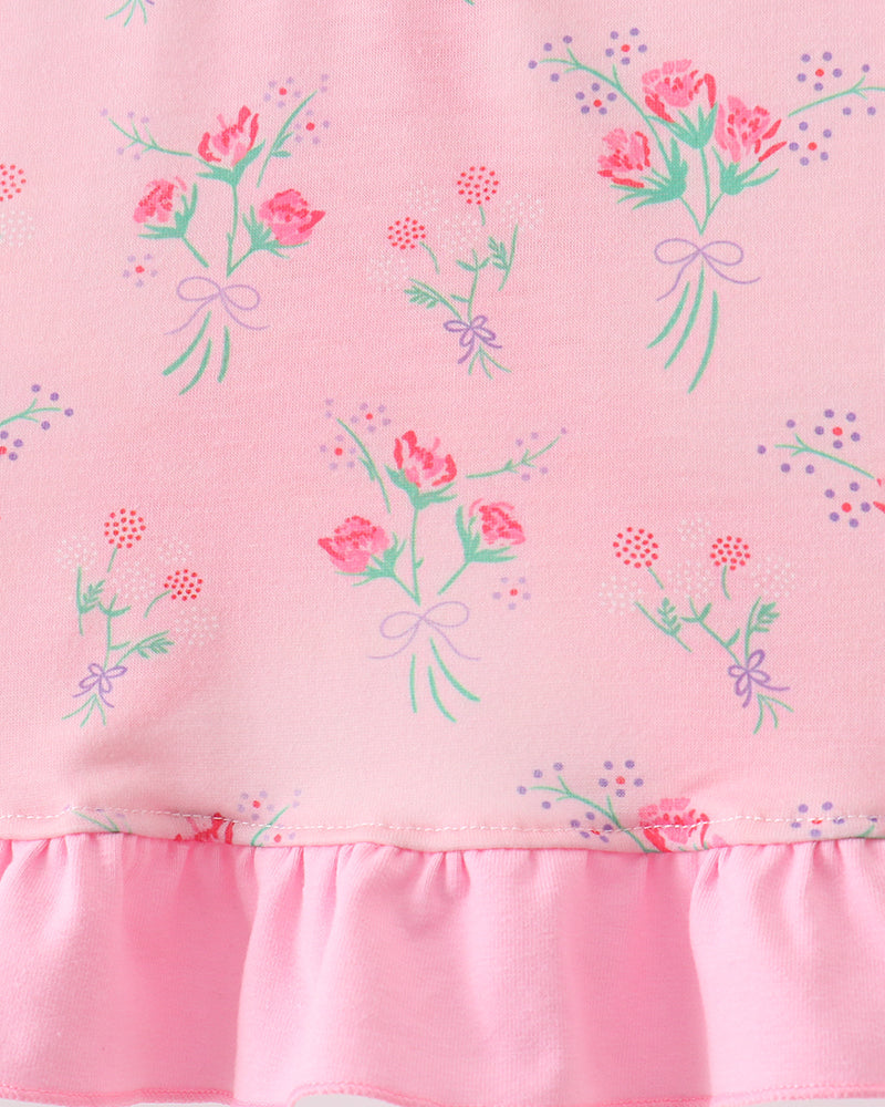 Pink fabric with floral patterns and a ruffled edge on a white background