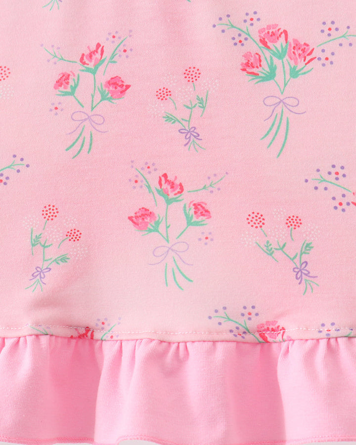 Pink fabric with floral patterns and a ruffled edge on a white background
