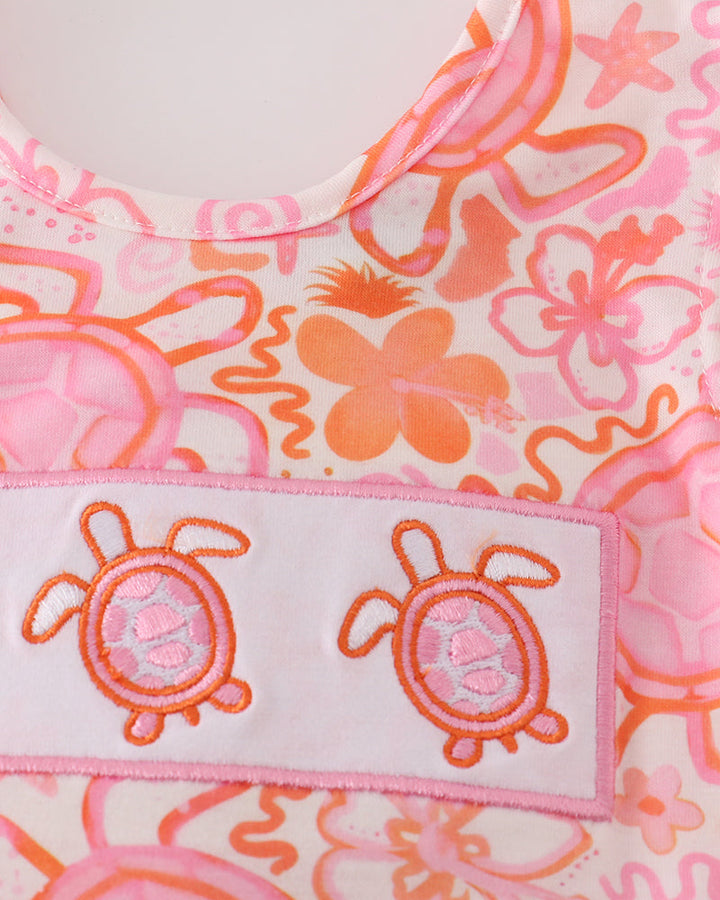 Close-up of a pink and orange floral pattern with turtle design on a label.