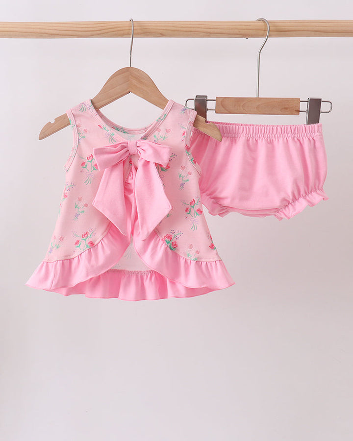 Pink baby outfit with top and bloomers on hangers against a white background