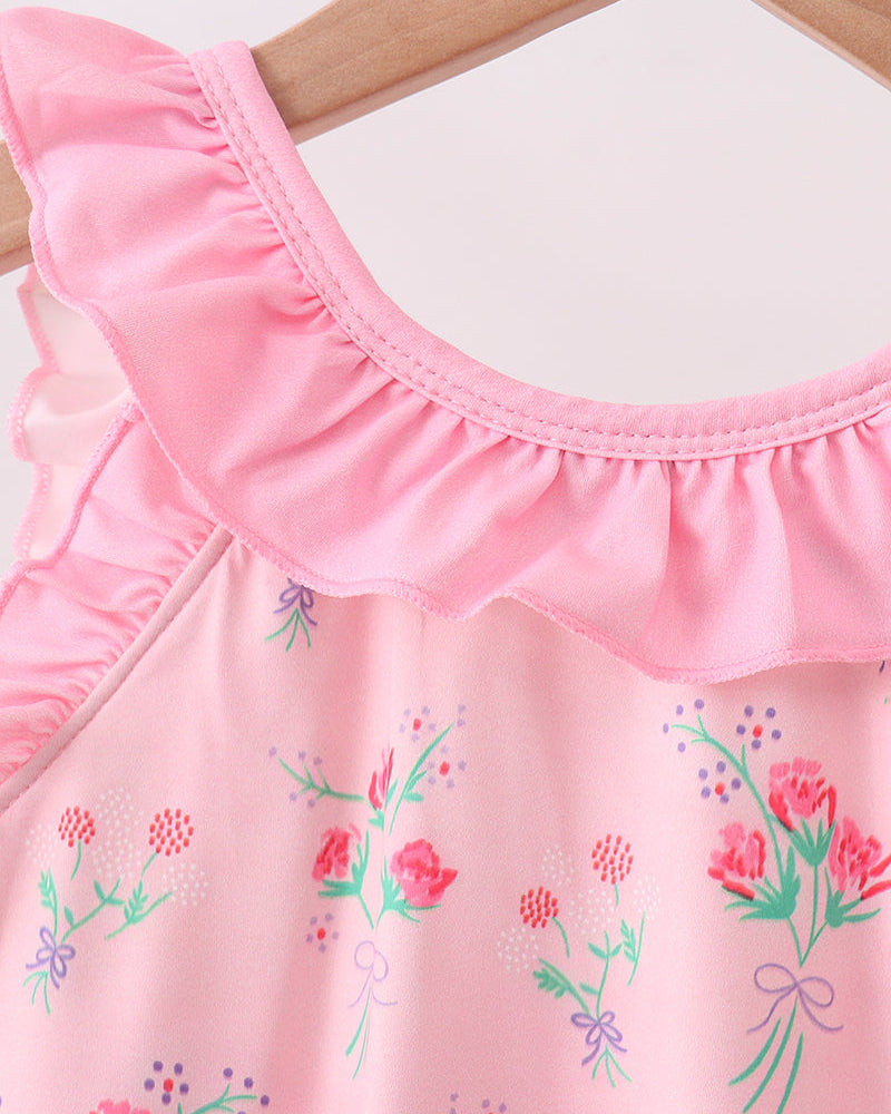 Pink swimsuit with floral embroidery on a wooden hanger