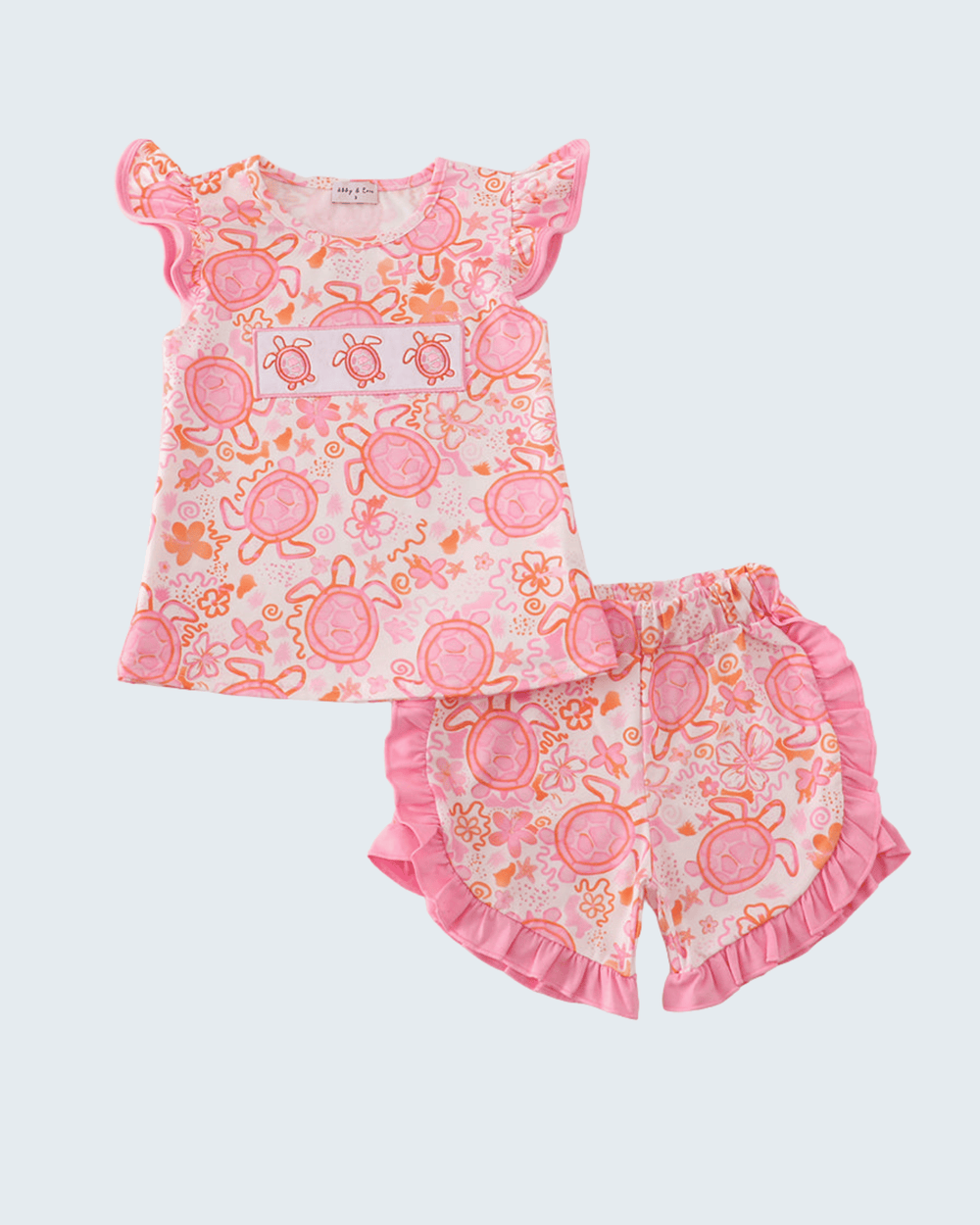 Children's outfit with pink and orange turtle pattern on a white background