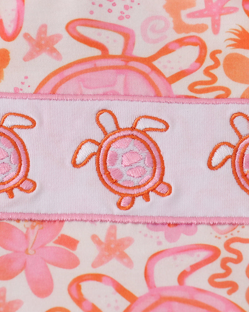 Fabric with sea-themed design featuring turtles, flowers, and bubbles on a pink background.