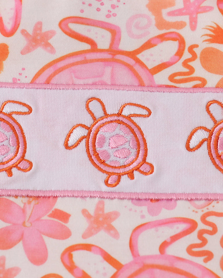 Fabric with sea-themed design featuring turtles, flowers, and bubbles on a pink background.