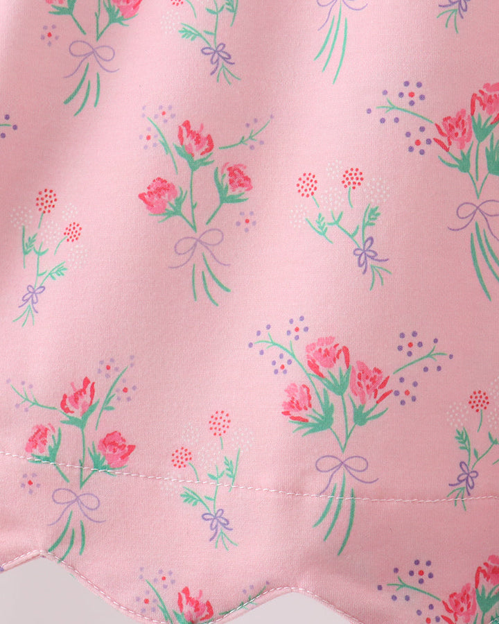 Floral pattern on a pink fabric with green leaves and red flowers.