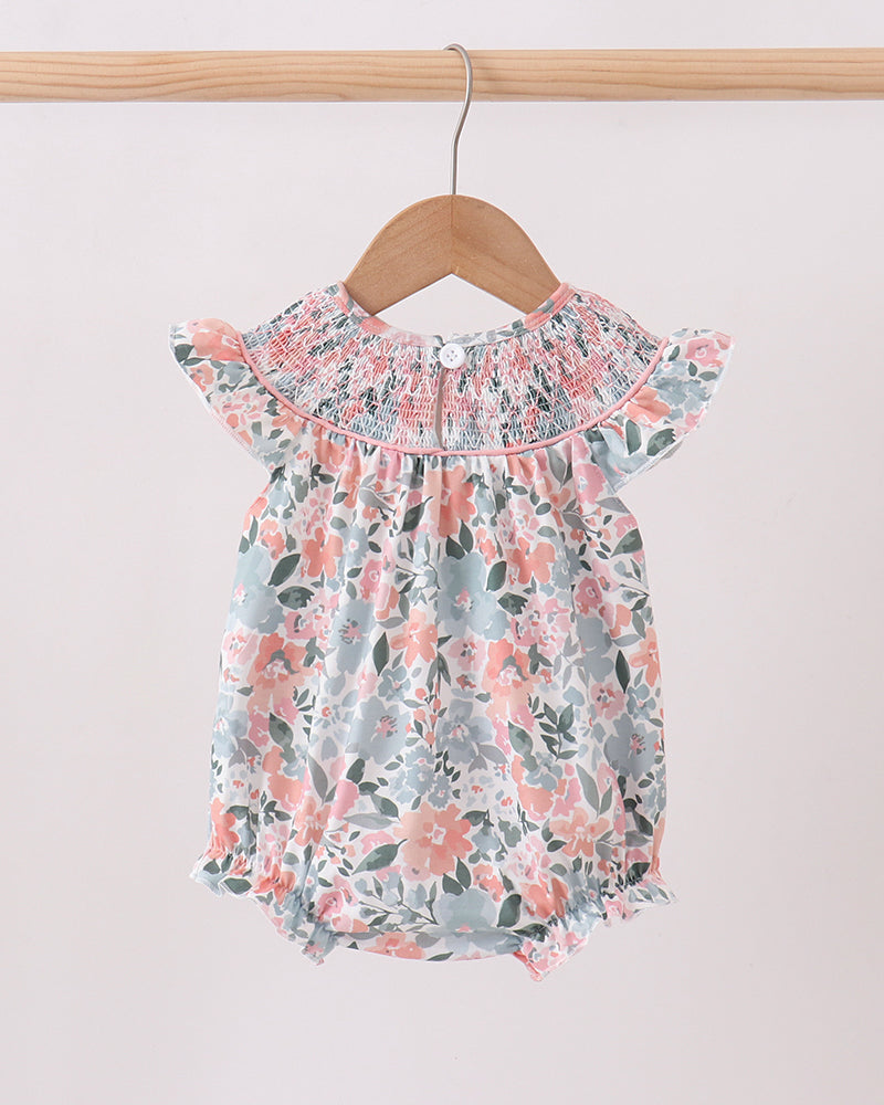 Floral baby romper on a hanger against a plain background