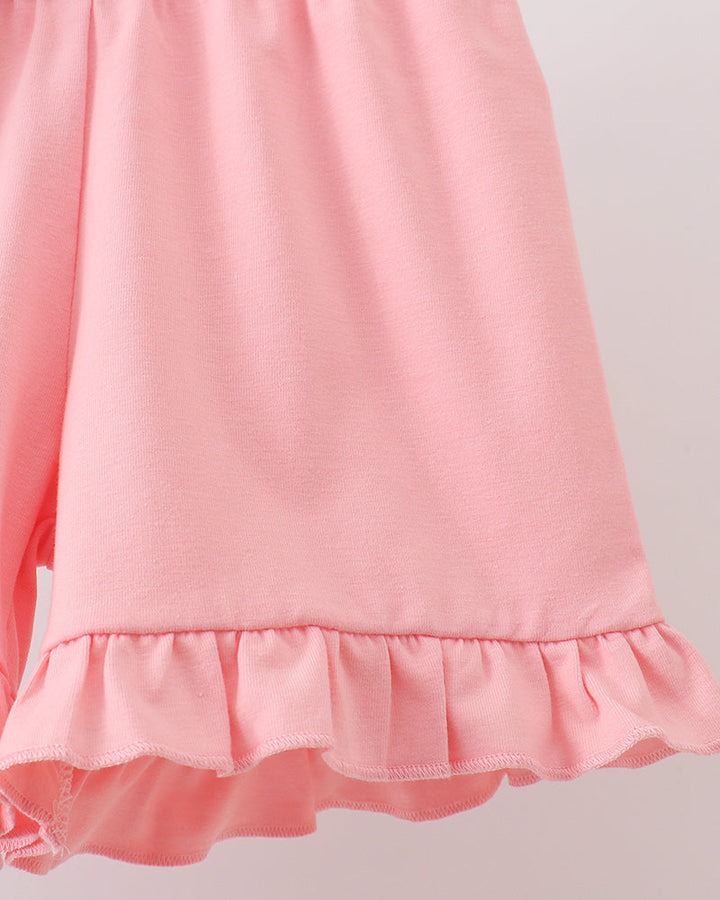 Close-up of a pink shorts with ruffled hem on a light gray background