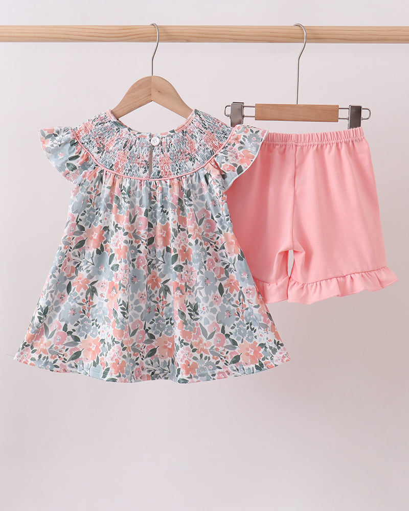 Floral top and pink shorts set hanging on a rack against a white background