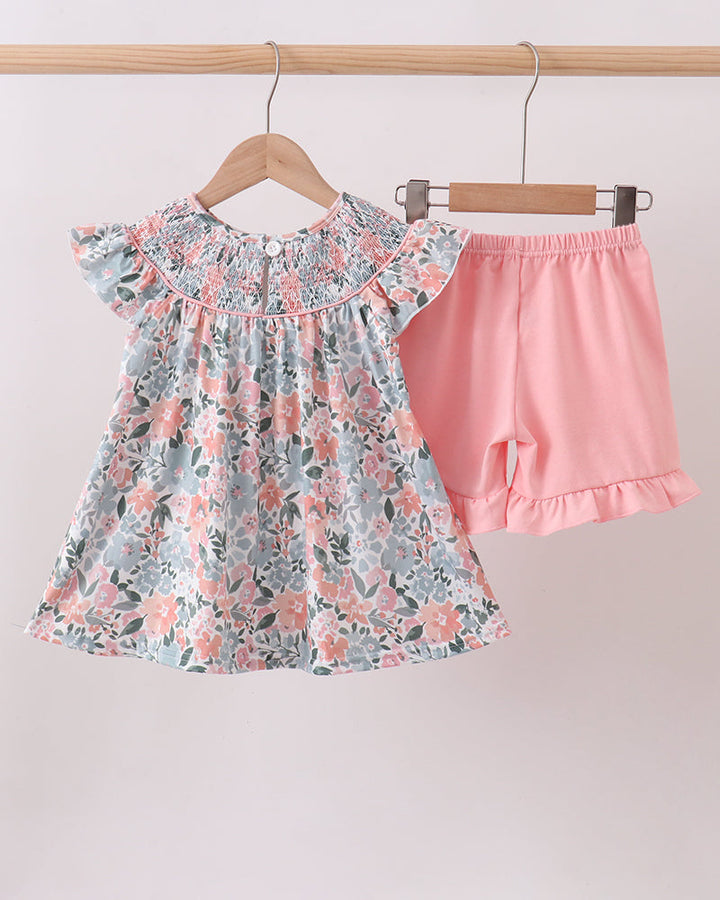 Floral top and pink shorts set hanging on a rack against a white background
