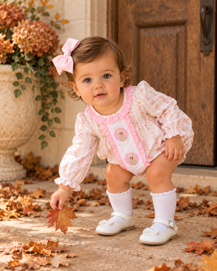 Baby wearing pink floral embroidered ruffle bubble romper with turkey appliques and long sleeves