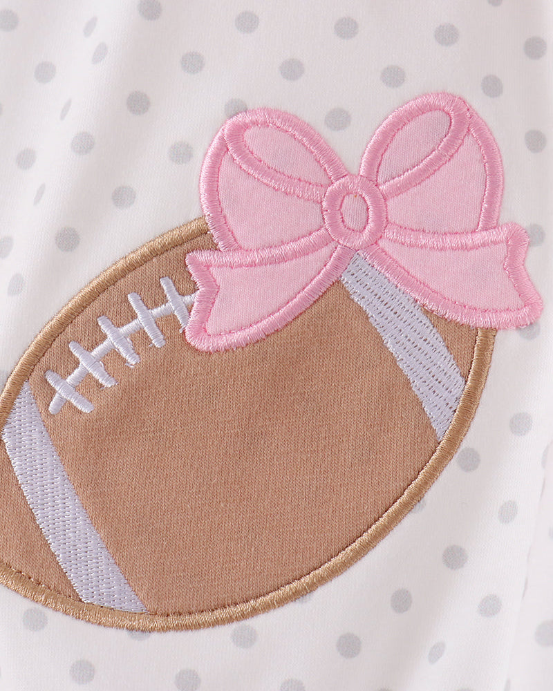 Brown football applique with pink bow and laced detail on white polka-dot romper