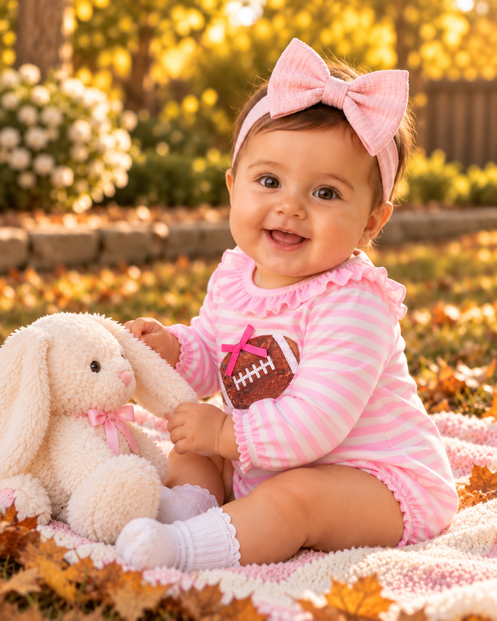 Pink striped romper on a baby with large bow headband and football sequin applique